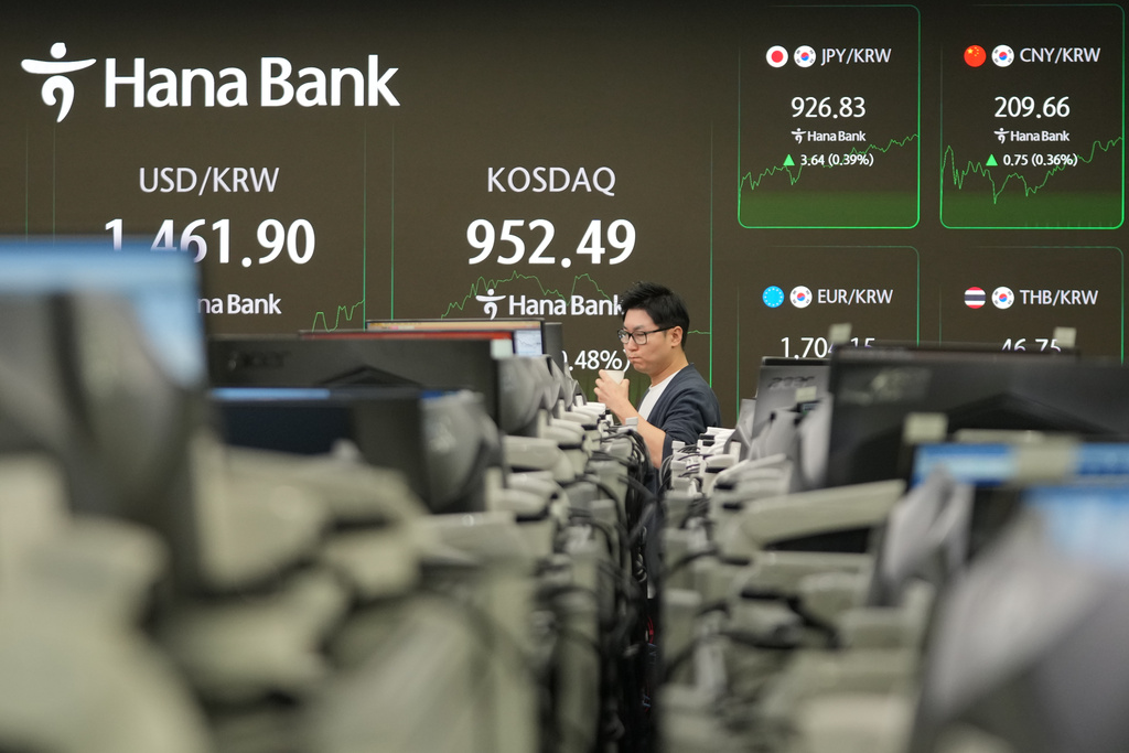 A dealer walks near the screens showing the foreign exchange rate between U.S. dollar and South Korean won and the Korean Securities Dealers Automated Quotations (KOSDAQ) at a dealing room of Hana Bank in Seoul, South Korea, Monday, Jan. 12, 2026. (AP Photo/Lee Jin-man)