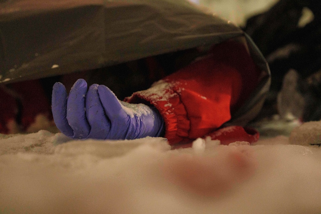 The body of a paramedic lies on the ground in the snow outside a residential building damaged by a Russian strike on Kyiv, Ukraine, Friday, Jan. 9, 2026. (AP Photo/Evgeniy Maloletka)