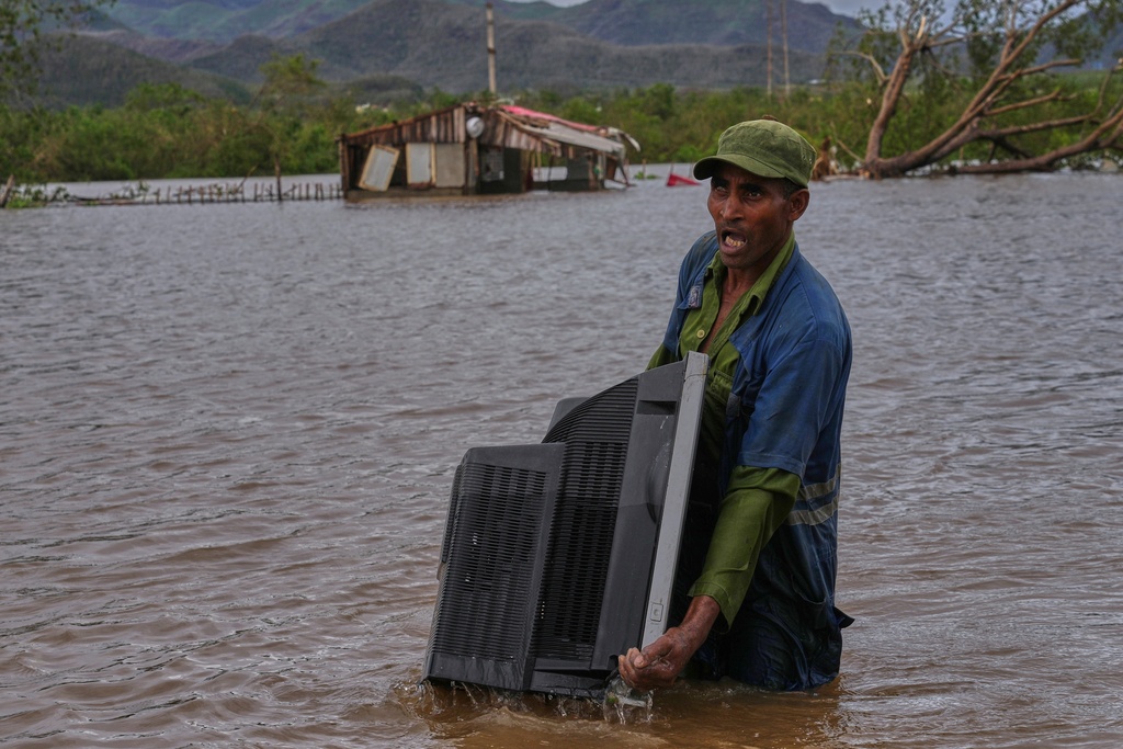 A man carries a TV from his home flooded by Hurricane Melissa in Santiago de Cuba, Wednesday, Oct. 29, 2025. (AP Photo/Ramon Espinosa)