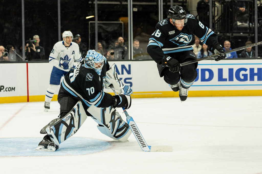 Utah Mammoth defenseman Nate Schmidt (88) jumps over Utah Mammoth goaltender Karel Vejmelka (70) hockey stick during the game against the Toronto Maple Leafs during the second period of an NHL hockey game Tuesday, Jan. 13, 2026, in Salt Lake City. (AP Photo/Melissa Majchrzak)