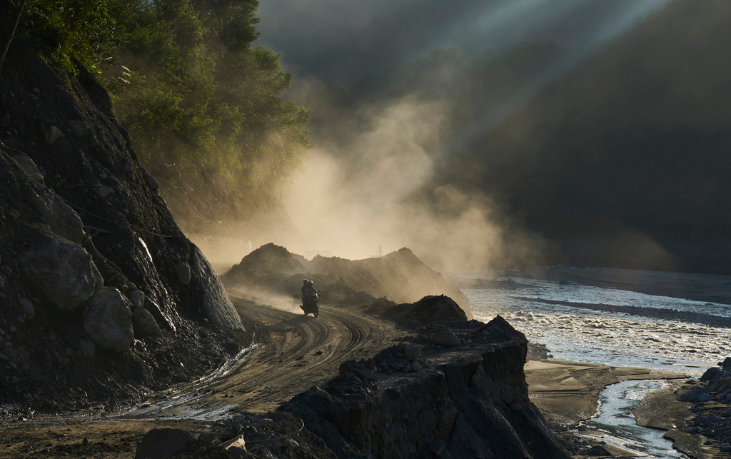 A motorcyclist travels along a newly built temporary road cut into a hillside to reconnect villages after flash floods destroyed the existing road in Nepal's Nuwakot district, Tuesday, Sept. 22, 2026. (AP Photo/Niranjan Shrestha)