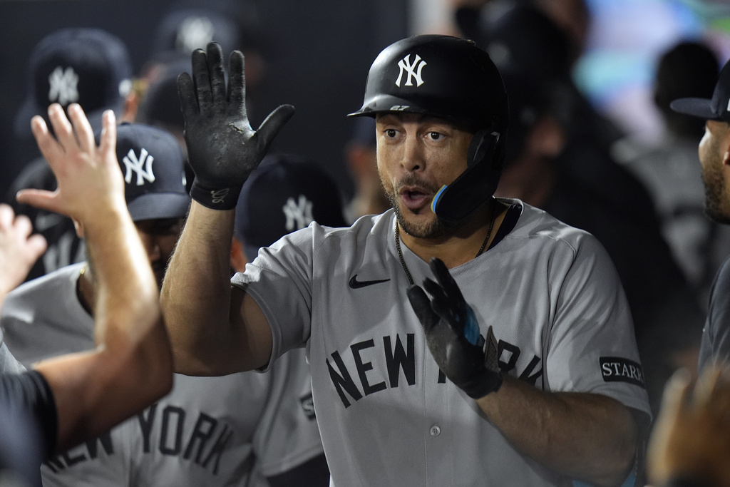 New York Yankees' Giancarlo Stanton celebrates in the dugout after hitting a solo home run off Tampa Bay Rays pitcher Shane Baz during the first inning of a baseball game Tuesday, Aug. 19, 2025, in Tampa, Fla. (AP Photo/Chris O'Meara)