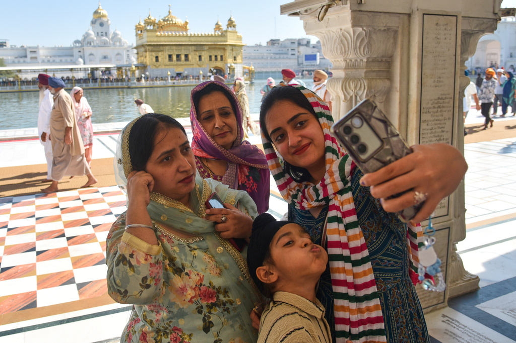 A family takes a selfie at the Golden Temple, Sikhism's holiest shrine, on Vaisakhi, a spring harvest festival for Sikhs and Hindus, in Amritsar, India, Tuesday, April 14, 2026. (AP Photo/Prabhjot Gill)
