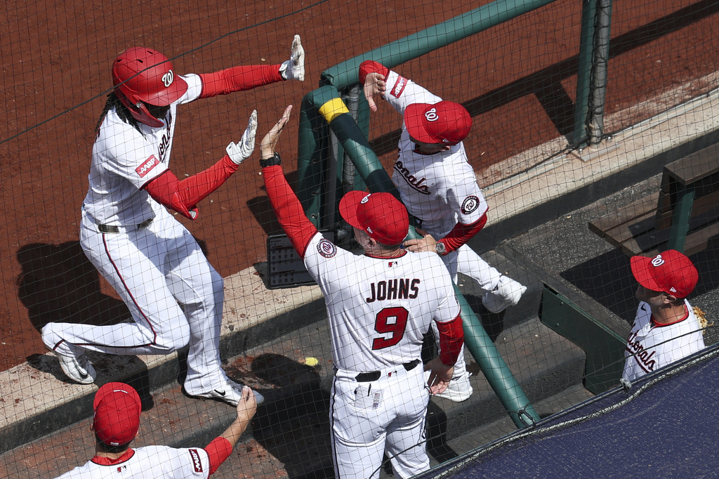 Washington Nationals' CJ Abrams, left, is greeted by teammates at the dugout after hitting a three run home run against the Los Angeles Dodgers during the first inning of an baseball game, Friday, April 3, 2026, in Washington. (AP Photo/Terrance Williams)