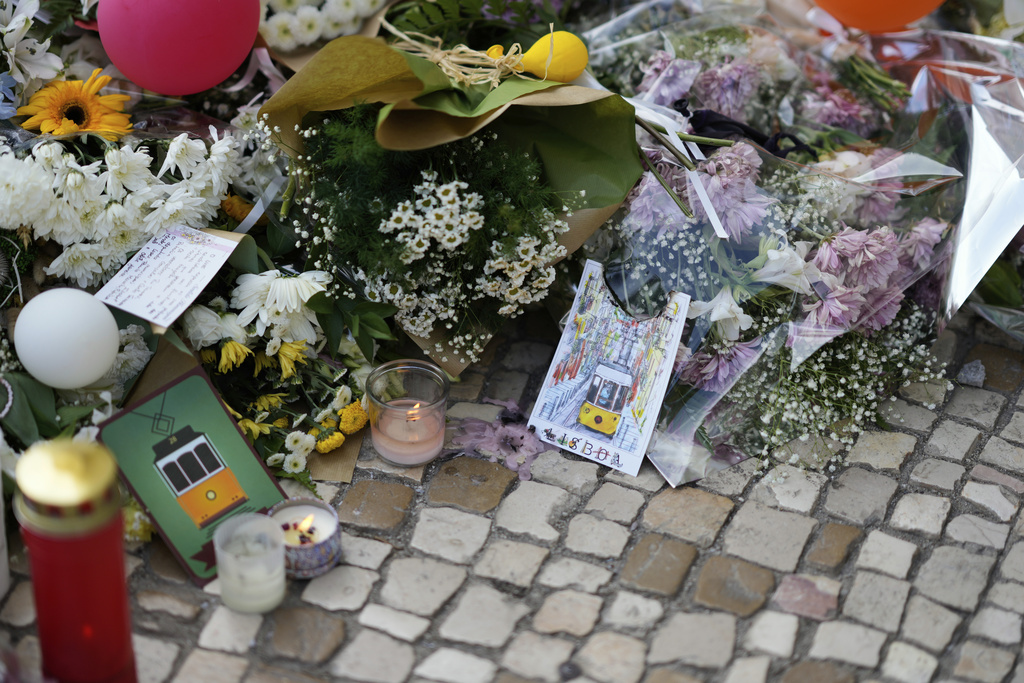 Lisbon postcards are placed among the flowers of a tribute to those that perished in the Gloria funicular, a tourist streetcar that derailed and crashed, in Lisbon, Saturday, Sept. 6, 2025. (AP Photo/Armando Franca)