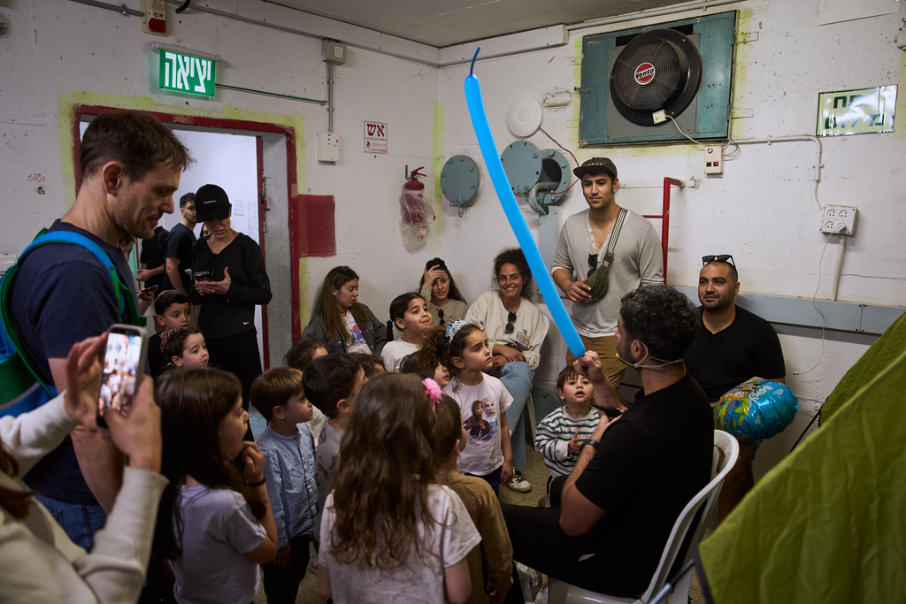 A man entertains children in a bomb shelter as air raid sirens warn of incoming missile strikes from Iran in Ramat Gan, Israel, Friday, March 20, 2026. (AP Photo/Oded Balilty)