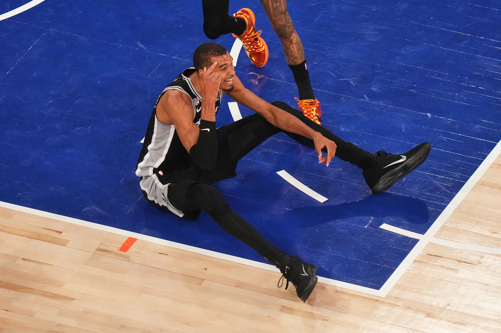 San Antonio Spurs forward Victor Wembanyama sits on the court after being knocked down during the first half of Game 4 of the NBA Finals basketball series against the New York Knicks, Wednesday, June 10, 2026, in New York. (AP Photo/Frank Franklin II)