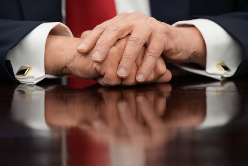 President Donald Trump rests his hands on the Resolute Desk as he speaks to reporters before signing an executive order in the Oval Office at the White House, Monday, Oct. 6, 2025, in Washington. (AP Photo/Jacquelyn Martin)