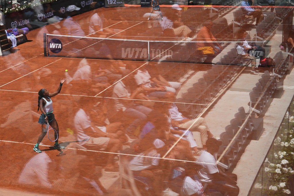 Fans are reflected in a glass partition as Coco Gauff, of the United States, serves the ball to United States' Iva Jovic during their match at the Italian Open tennis tournament in Rome, Monday, May 11, 2026. (AP Photo/Alessandra Tarantino)