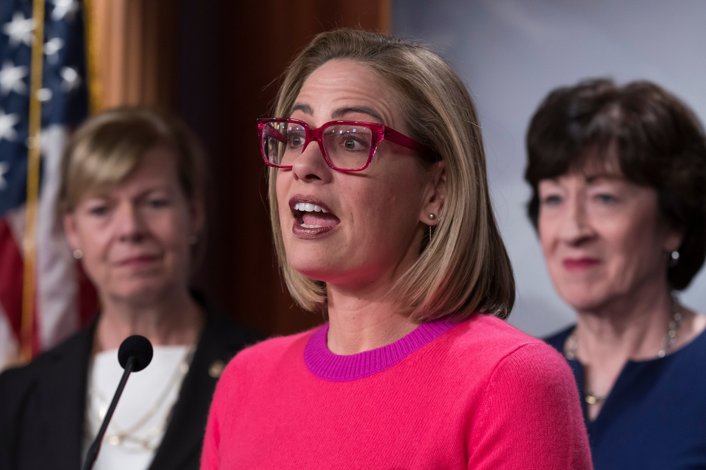 FILE - Sen. Kyrsten Sinema, D-Ariz., flanked by Sen. Tammy Baldwin, D-Wis., left, and Sen. Susan Collins, R-Maine, speaks to reporters following Senate passage of the Respect for Marriage Act, at the Capitol in Washington, Nov. 29, 2022. (AP Photo/J. Scott Applewhite, File)