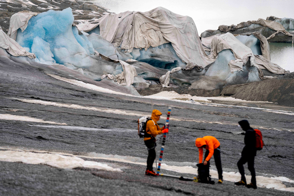 FILE — Swiss Federal Institute of Technology glaciologist and head of the Swiss measurement network 'Glamos', Matthias Huss, center, and his assistants arrive at the Rhone glacier near Goms, Switzerland, June 16, 2023. (AP Photo/Matthias Schrader)