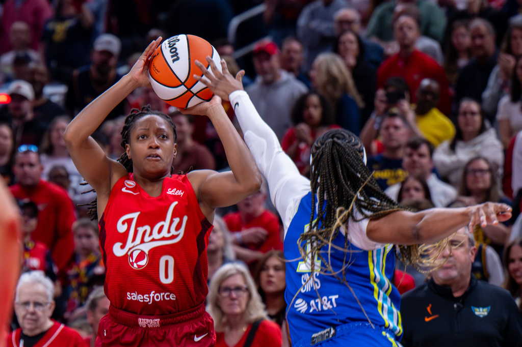 Indiana Fever guard Kelsey Mitchell (0) shoots over Dallas Wings guard Odyssey Sims (1) during the first half of an WNBA basketball in Indianapolis, Saturday, May 9, 2026. (AP Photo/Doug McSchooler)