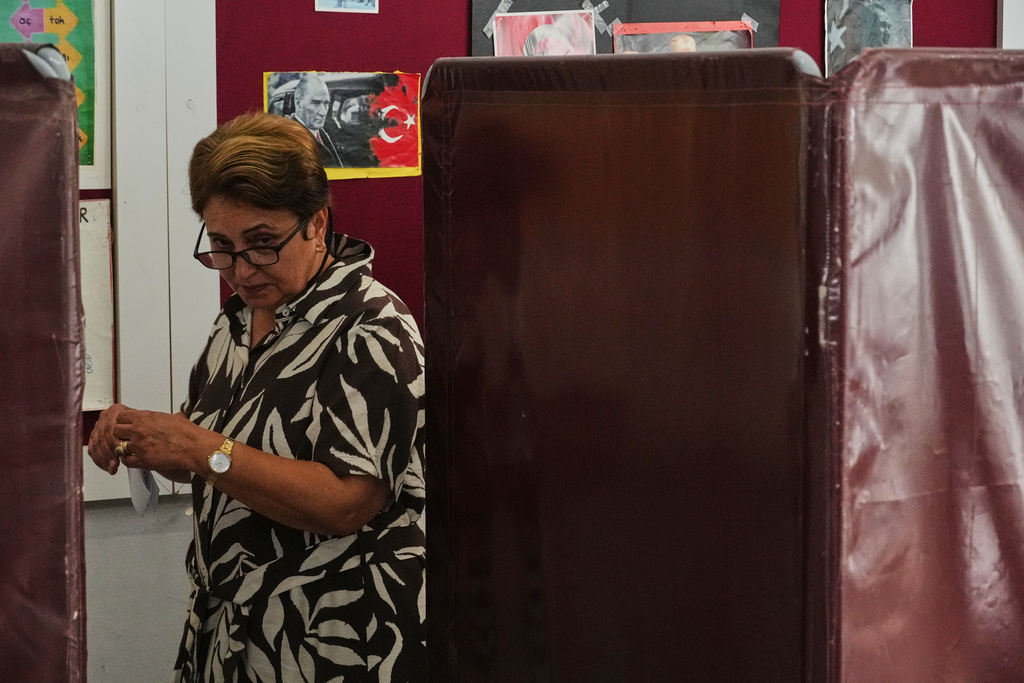 A woman leaves a booth after casting her ballot at a polling station during the Turkish Cypriot leadership election in the Turkish-occupied northern part of the divided capital Nicosia, Cyprus, Sunday, Oct. 19, 2025. (AP Photo/Petros Karadjias)