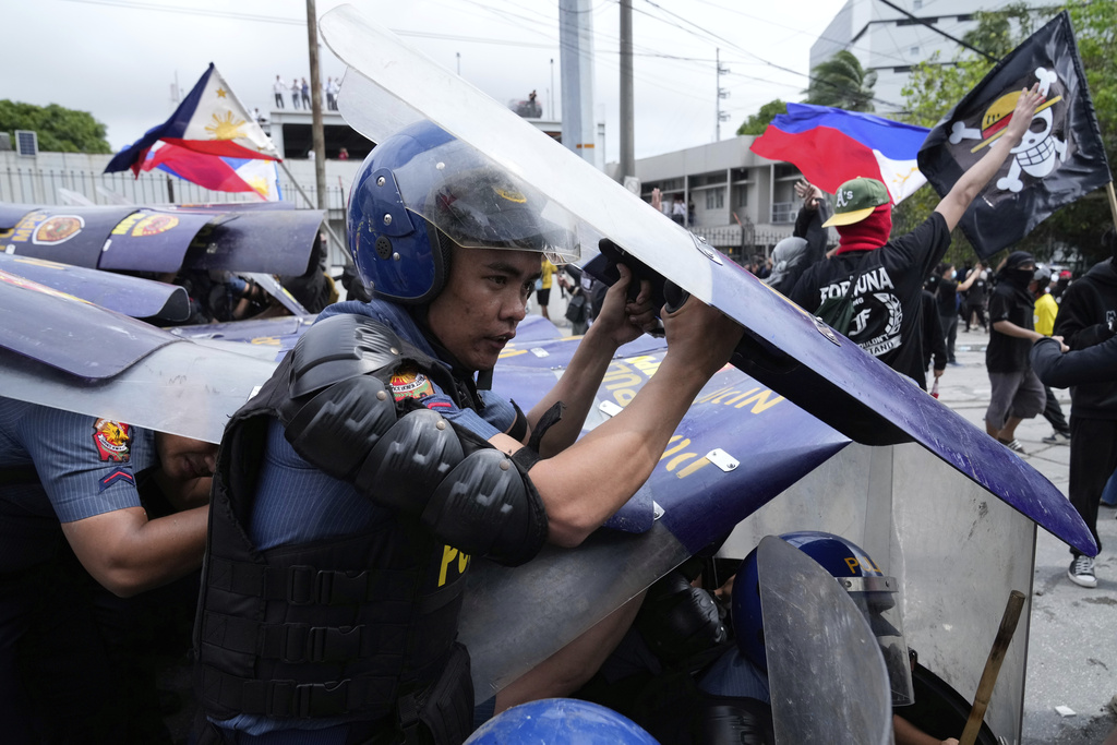 A policeman uses his shield following clashes with protesters as they tried to enter the Malacanang presidential palace compound in Manila, Philippines on Sunday, Sept. 21, 2025. (AP Photo/Aaron Favila)