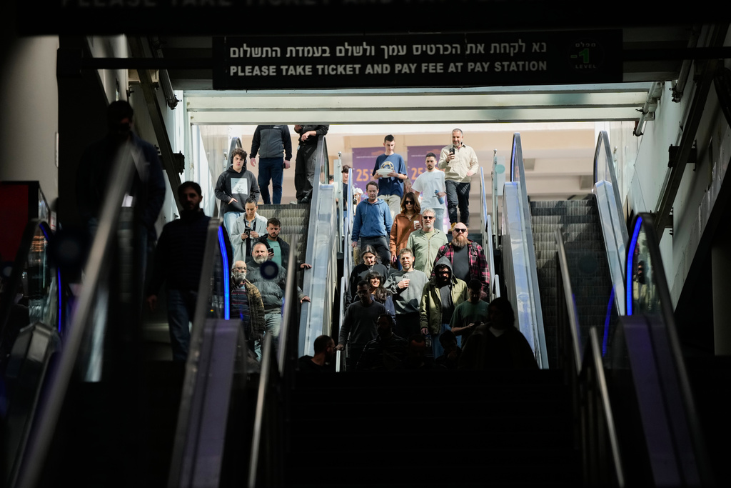 People take shelter in an underground parking garage as air raid sirens warn of incoming missiles launched by Iran toward Tel Aviv, Israel, Sunday, March 1, 2026. (AP Photo/Ohad Zwigenberg)