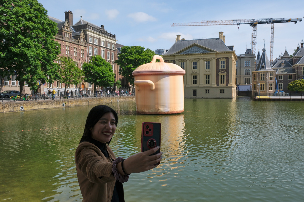 A woman takes a selfie in front of an art installation titled Like a pan in the water by Studio Job as part of the BlowUp Jubilee Art walk in the Hague, Netherlands, Thursday, May 21, 2026. (AP Photo/Patrick Post)