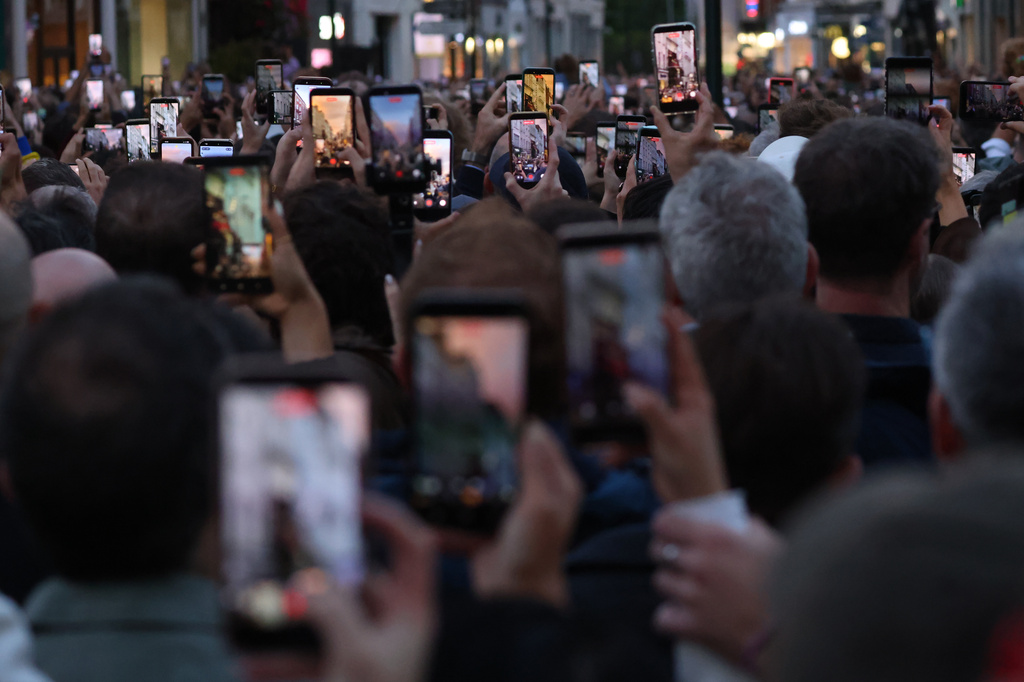 Members of the crowd take photos on their phones as U2 perform an impromptu concert from a balcony in central Dublin, Ireland , Friday, Sept. 25, 2026. (AP Photo/Peter Morrison)