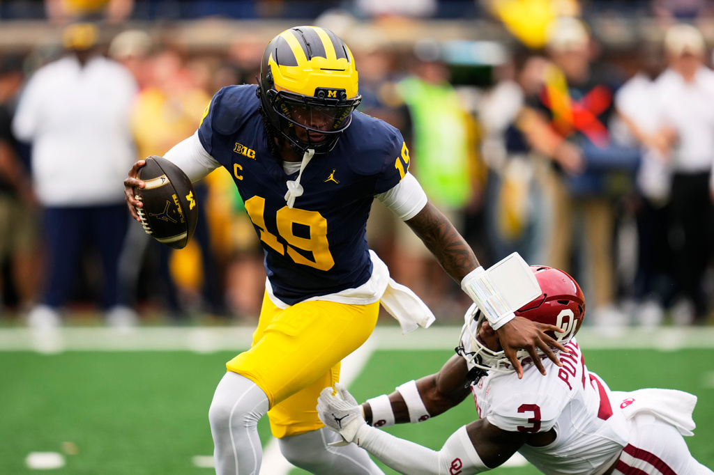 Michigan quarterback Bryce Underwood (19) escapes the tackle of Oklahoma defensive back Reggie Powers III (3) in the first half of an NCAA college football game Saturday, Sept. 12, 2026, in Ann Arbor, Mich. (AP Photo/Paul Sancya)