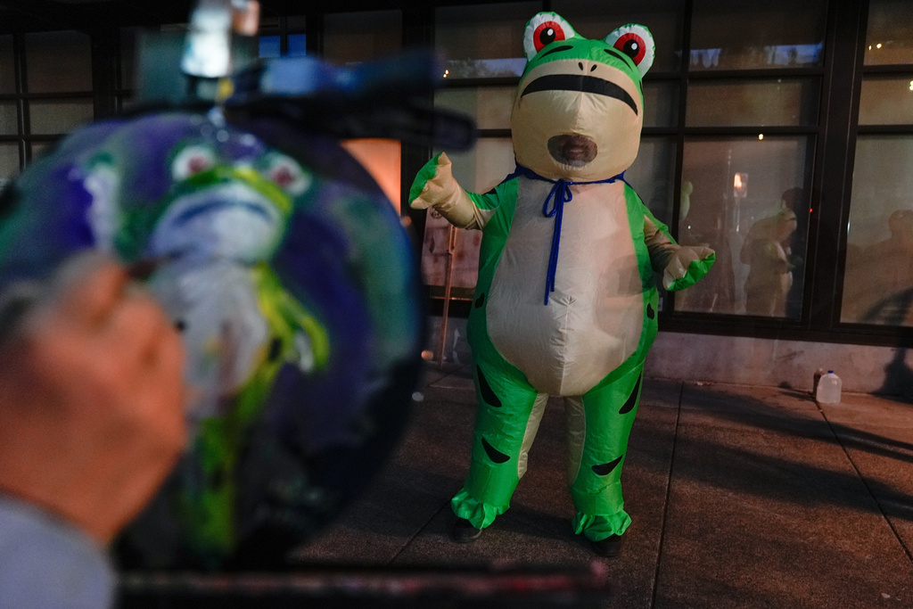 A person paints a portrait of a demonstrator dressed in an inflatable costume outside a United States Immigration and Customs Enforcement (ICE) facility on Tuesday, Oct. 21, 2025, in Portland, Ore. (AP Photo/Jenny Kane)