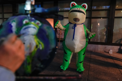 A person paints a portrait of a demonstrator dressed in an inflatable costume outside a United States Immigration and Customs Enforcement (ICE) facility on Tuesday, Oct. 21, 2025, in Portland, Ore. (AP Photo/Jenny Kane) A person paints a portrait of a demonstrator dressed in an inflatable costume outside a United States Immigration and Customs Enforcement (ICE) facility on Tuesday, Oct. 21, 2025, in Portland, Ore. (AP Photo/Jenny Kane)