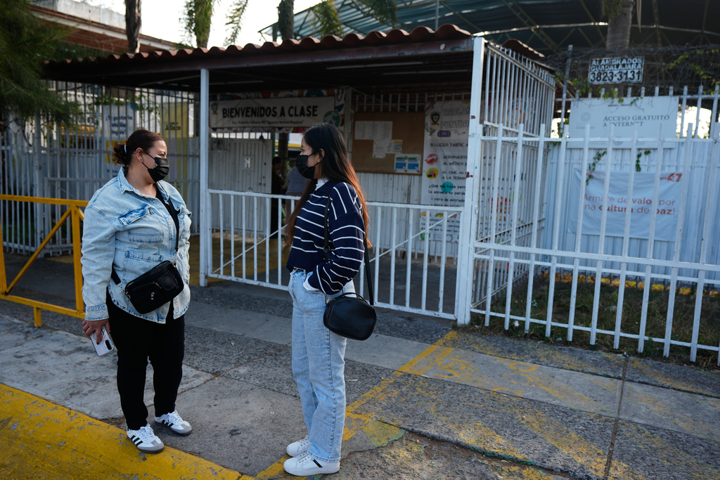 Parents of students wear face masks, made mandatory amid a measles outbreak, as they wait outside of a public school in Guadalajara, Mexico, Thursday, Feb. 5, 2026. (AP Photo/Fernando Llano