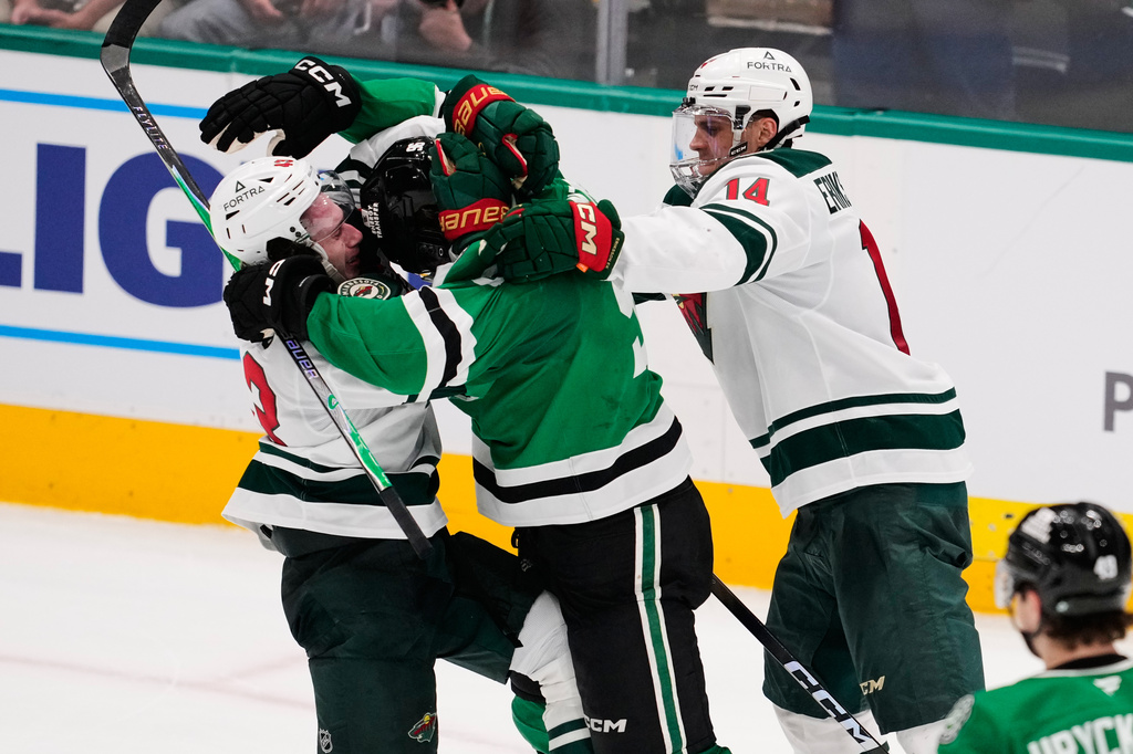 Minnesota Wild's Quinn Hughes, left, Dallas Stars' Mikko Rantanen, center, and Joel Eriksson Ek (14) fight in the third period of an NHL hockey game Thursday, April 9, 2026, in Arlington, Texas. (AP Photo/Tony Gutierrez)