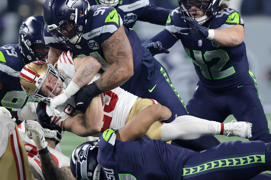 FILE - San Francisco 49ers running back Christian McCaffrey (23) is tackled by Seattle Seahawks defensive tackle Byron Murphy II (91) and linebacker Uchenna Nwosu (7) in an NFL football divisional playoff game, Jan. 17, 2026, in Seattle. (AP Photo/John Froschauer, File)