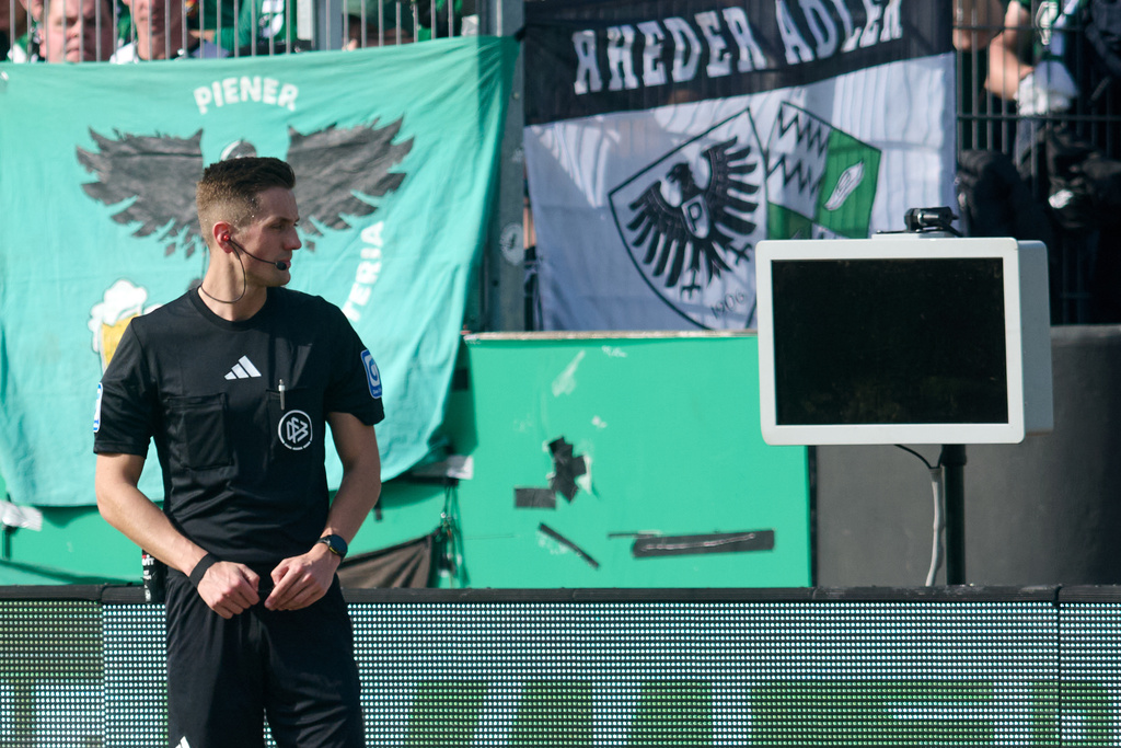 Referee Felix Bickel stands in front of the dark screen as he tries to review a VAR decision on a penalty kick for Berlin during the Bundesliga 2 soccer game between Muenster and Hertha Berlin in Muenster, Germany, Sunday March 8, 2026. (Bernd Thissen/dpa via AP)