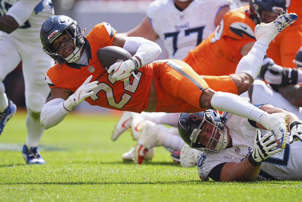 Denver Broncos safety Brandon Jones (22) recovers a fumble over Tennessee Titans guard Kevin Zeitler, right, during the first half of an NFL football game Sunday, Sept. 7, 2025, in Denver. (AP Photo/David Zalubowski)