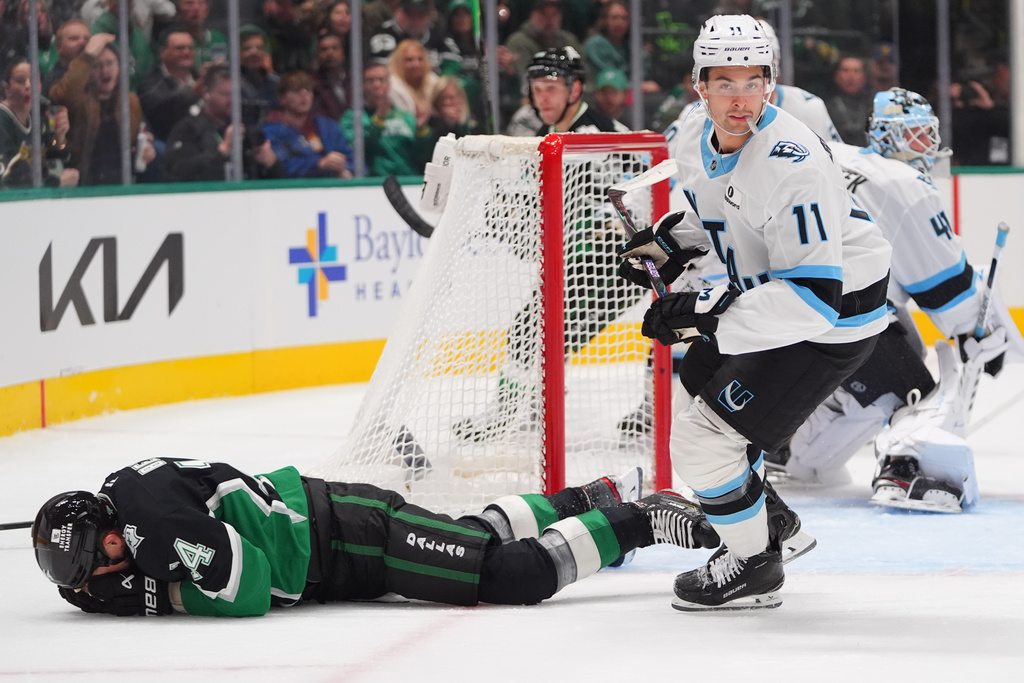 After getting slashed, Dallas Stars left wing Jamie Benn, left, lies on the ice as Utah Mammoth right wing Dylan Guenther (11) skates by during the first period of an NHL hockey game Friday, Nov. 28, 2025, in Dallas. (AP Photo/LM Otero)