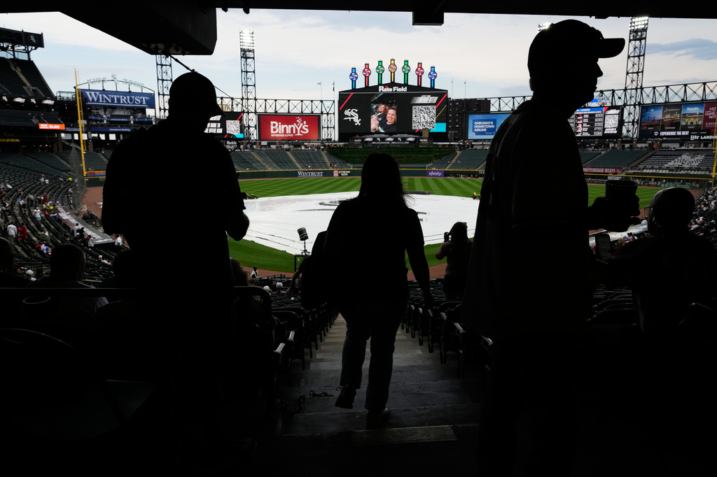A tarp covers the infield as baseball fans wait during a rain delay before a baseball game between the Atlanta Braves and the Chicago White Sox in Chicago, Thursday, June 11, 2026. (AP Photo/Nam Y. Huh)