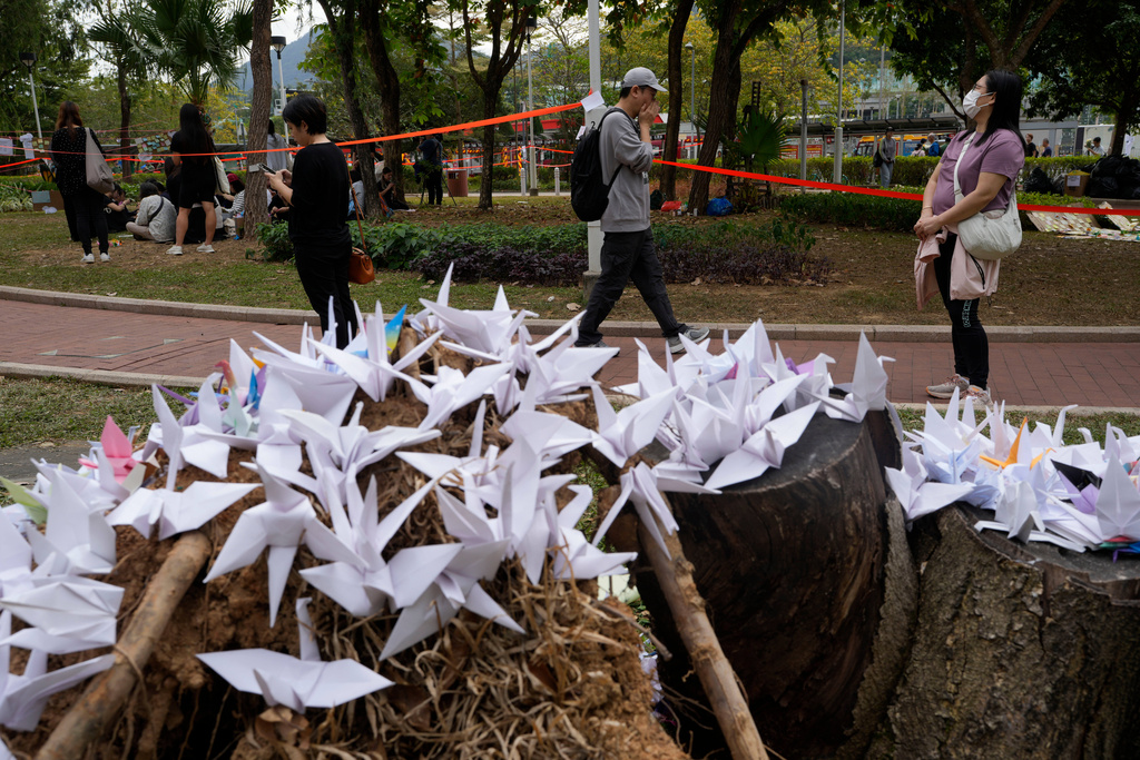 People pass near paper cranes placed near the site of a deadly fire at Wang Fuk Court, a residential estate in the Tai Po district of Hong Kong's New Territories on Tuesday, Dec. 2, 2025. (AP Photo/Ng Han Guan)