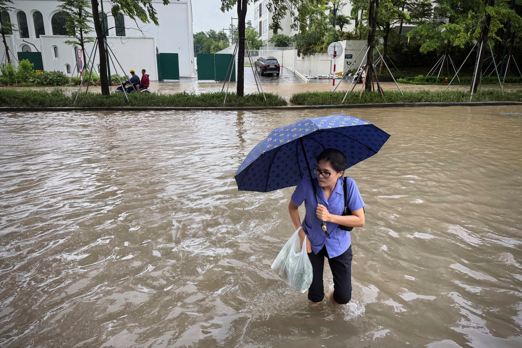 A woman crosses a flooded street caused by Typhoon Kajiki in Hanoi, Vietnam, Tuesday, Aug. 26, 2025. (AP Photo/Hau Dinh)
