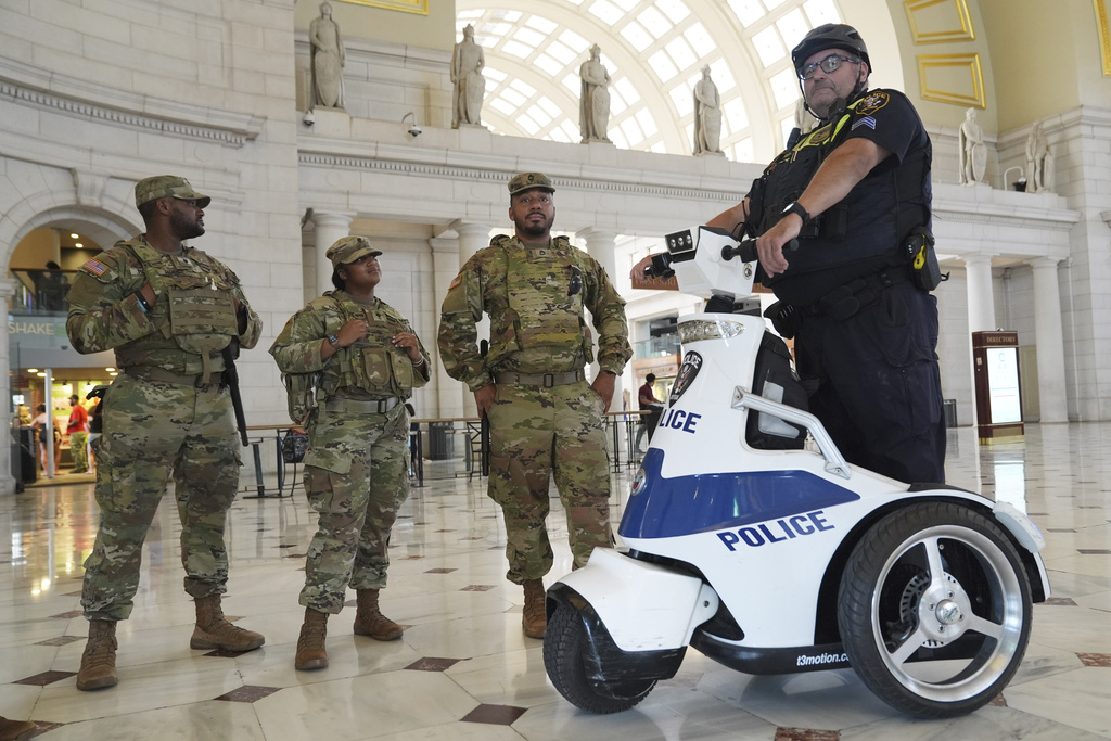 National Guard personnel talk to a member of the Amtrak Police, right, as travelers arrive at Union Station near the Capitol, in Washington, Friday, Aug. 15, 2025, in Washington. (AP Photo/Jacquelyn Martin)