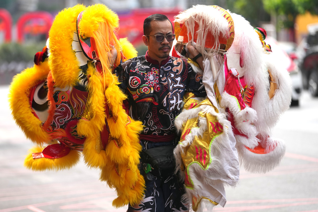 A dancer holds the heads of lion dance costumes during Chinese Lunar New Year in Bangkok, Thailand, Tuesday, Feb. 17, 2026. (AP Photo/Sakchai Lalit)