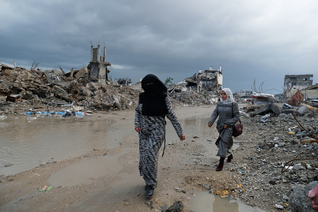 Palestinians walk through the rubble amid stormy weather in Gaza City Thursday, Dec. 11, 2025. (AP Photo/Jehad Alshrafi)