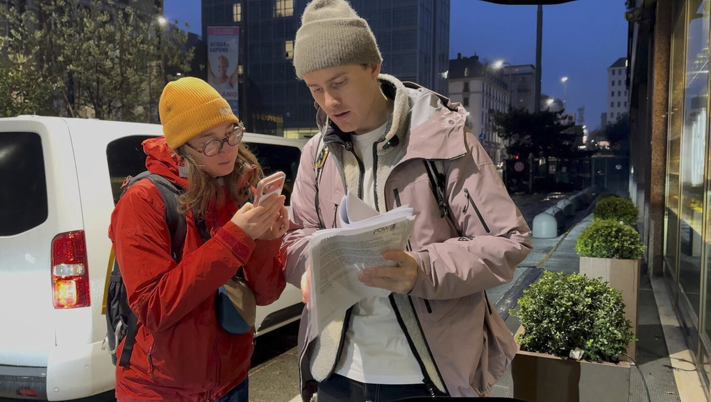 CAPTIONS CORRECTS SPELLING Norwegian skier Nikolai Schirmer and Protect Our Winters Italy General Manager Giorgia Garancini look over a “ski fossil free” petition with over 20,000 signatures that Schirmer privately handed to the IOC's head of sustainability, Julie Duffus, two days before the Opening Ceremony for the 2026 Milan Cortina Winter Olympics, Wednesday, Feb. 4, 2026, in Milan. (AP Photo/Fernanda Figueroa)
