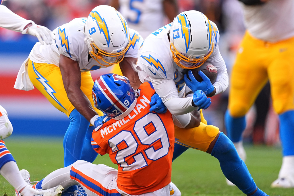 Denver Broncos cornerback Ja'quan McMillian (29) tackles Los Angeles Chargers wide receiver Keenan Allen (13) during the first half of an NFL football game Sunday, Jan. 4, 2026, in Denver. (AP Photo/David Zalubowski)