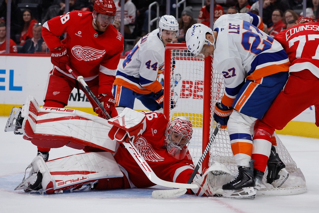 Detroit Red Wings goaltender John Gibson (36) tries to grab the puck against New York Islanders left wing Anders Lee (27) trying to score during the first period of an NHL hockey game Tuesday, Dec. 16, 2025, in Detroit. (AP Photo/Duane Burleson)