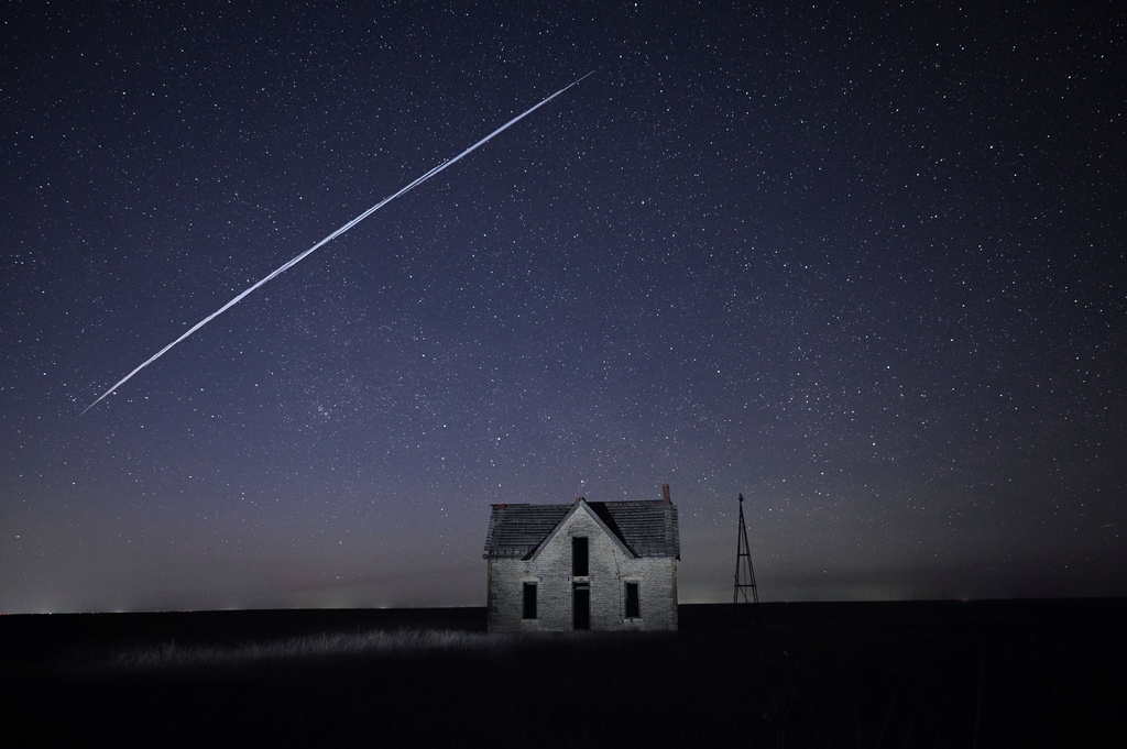 FILE - In this long exposure photo, a string of SpaceX StarLink satellites passes over an old stone house near Florence, Kan., on May 6, 2021. (AP Photo/Reed Hoffmann, File)