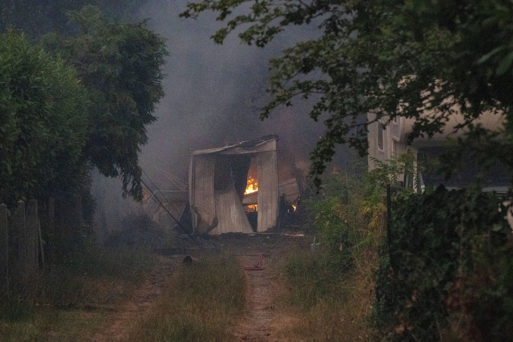 A burning barn is seen next to a farm house during wildfires near Le Porge, western France, Thursday, July 23, 2026. (AP Photo/Caroline Blumberg)