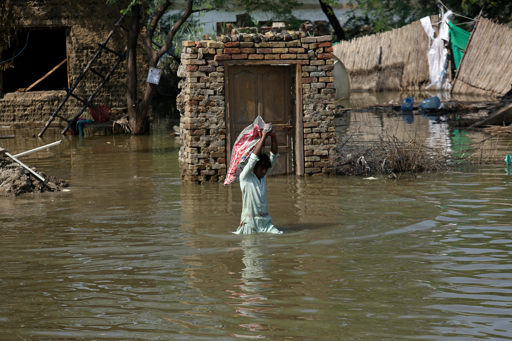 FILE - A man carries usable belongings salvaged from his flood-hit home across a flooded area in Shikarpur district of Sindh province, of Pakistan, Wednesday, Aug. 31, 2022. (AP Photo/Fareed Khan, File)
