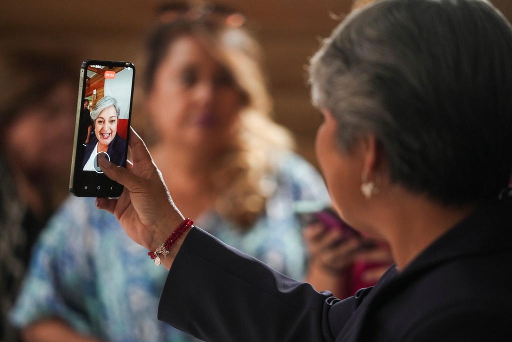 Presidential candidate Jeannette Jara of the Unidad por Chile coalition records a video during a meeting with local leaders in the La Pintana neighborhood of Santiago, Chile, Monday, Nov. 17, 2025. (AP Photo/Esteban Felix)