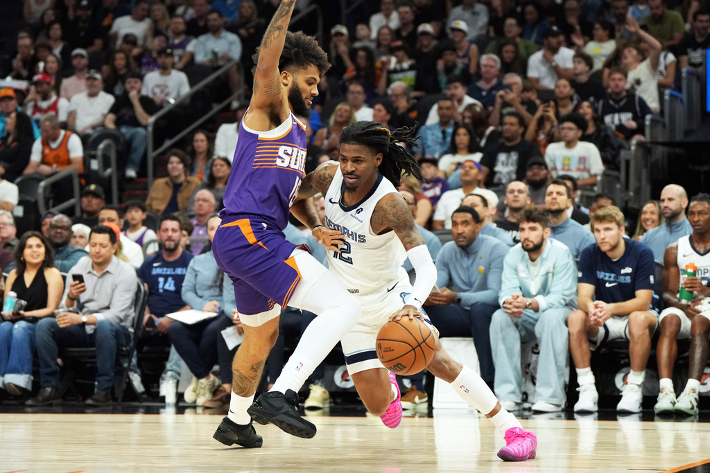 Memphis Grizzlies guard Ja Morant (12) drives on Phoenix Suns forward Isaiah Livers during the first half of an NBA basketball game, Wednesday, Oct. 29, 2025, in Phoenix. (AP Photo/Rick Scuteri)