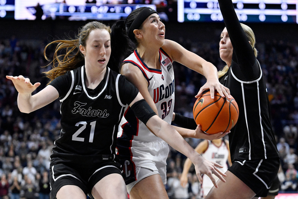 UConn guard Caroline Ducharme (33) looks to shoot while guarded by Providence guard Payton Dunbar (21) and Providence forward Ashley Dinges in the first half of an NCAA college basketball game, Sunday, Feb. 22, 2026, in Storrs, Conn. (AP Photo/Jessica Hill)