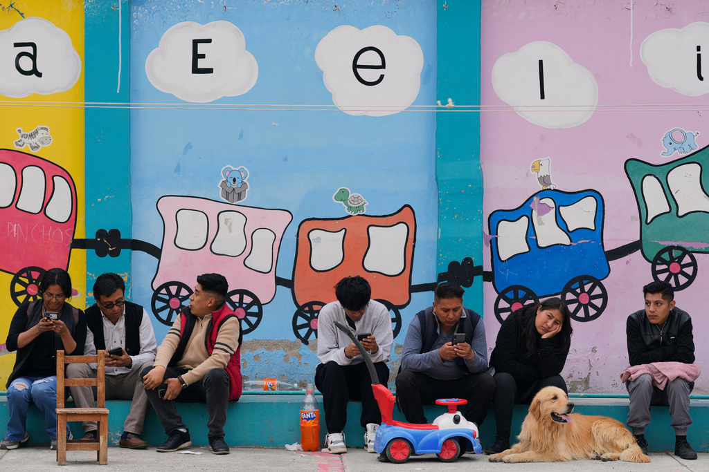 People gather outside a polling station to wait for results after polls closed during a presidential runoff election in La Paz, Bolivia, Sunday, Oct. 19, 2025. (AP Photo/Juan Karita)