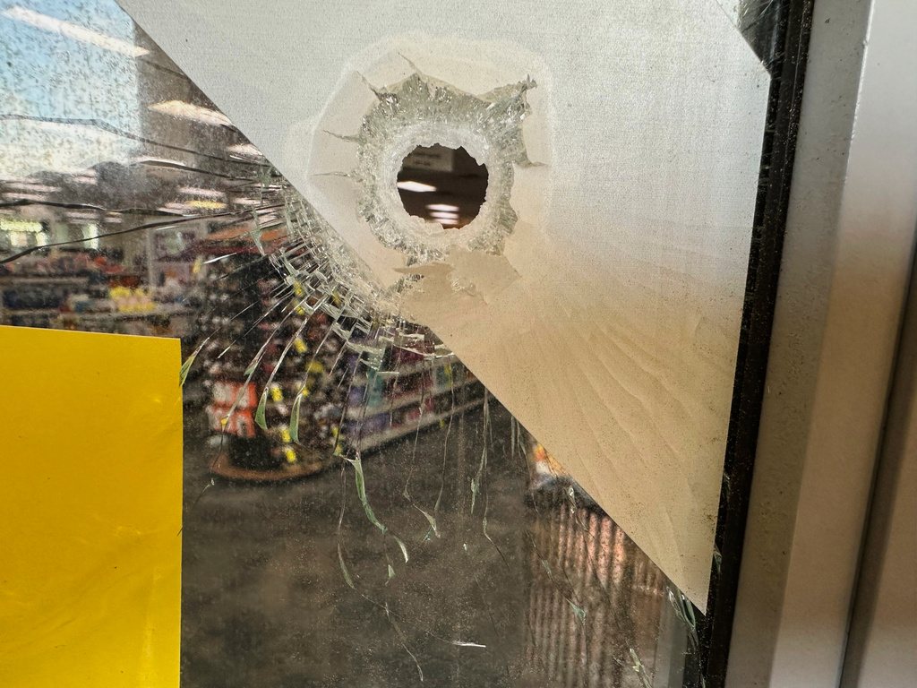 A bullet hole is visible in the door of a CVS pharmacy on Saturday, August 9, 2025, near where police say a man was shooting at the headquarters of the U.S. Centers for Disease Control and Prevention in Atlanta (AP Photo/Jeff Amy)