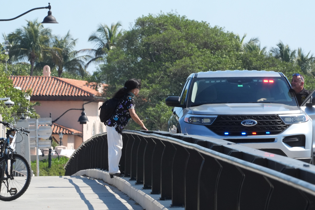 A Palm Beach County sheriff deputy talks to a bicyclist on the bridge leading to Mar-a-Lago Sunday, Feb. 22, 2026, in Palm Beach, Fla. The U.S. Secret Service announced Sunday that an armed man was shot and killed after entering the secure perimeter of Mar-a-Lago, President Donald Trump's resort. (AP Photo/Marta Lavandier)