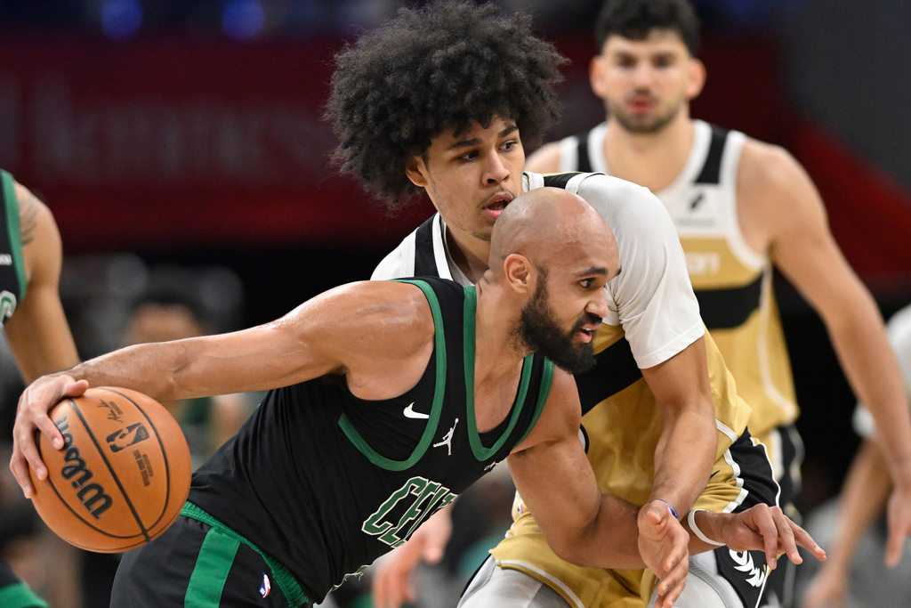 Boston Celtics guard Derrick White, front, dribbles against Washington Wizards forward Kyshawn George, top, during the first half of an NBA basketball game Thursday, Dec. 4, 2025, in Washington. (AP Photo/John McDonnell)
