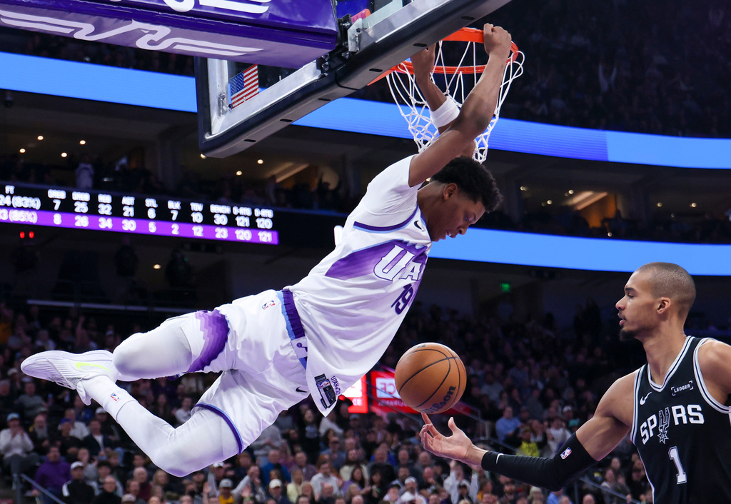 Utah Jazz guard Ace Bailey (19) hangs from the rim after dunking against the San Antonio Spurs during the second half of an NBA basketball game, Thursday, Jan. 22, 2026, in Salt Lake City. (AP Photo/Rob Gray)